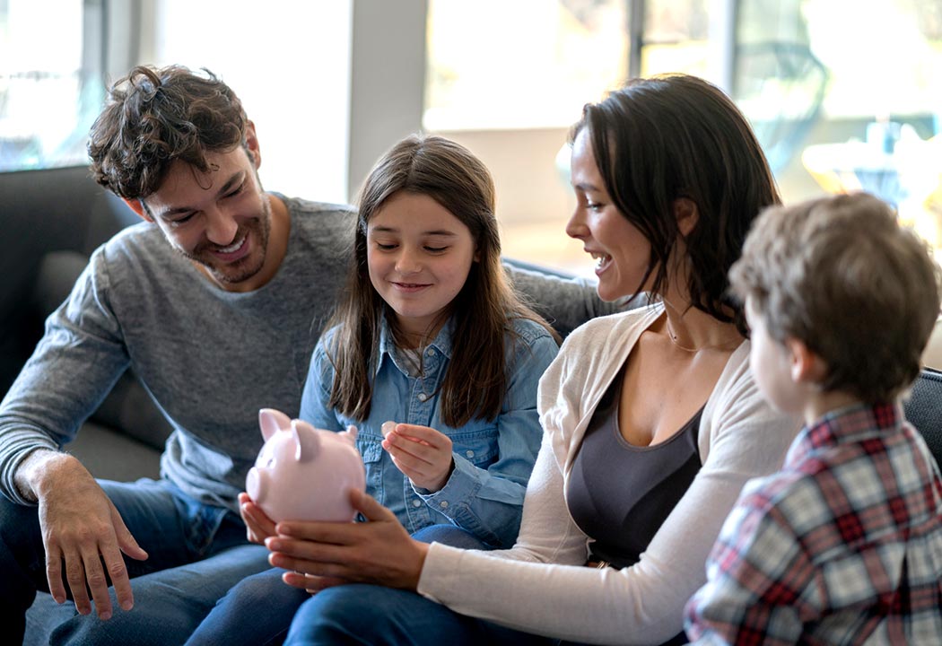 Parents and two kids holding a piggy bank.