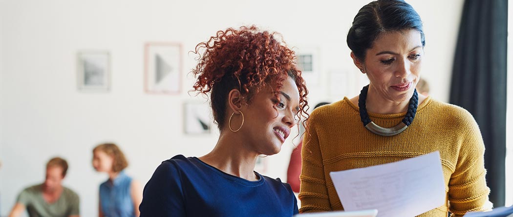 Two female coworkers looking at paperwork.