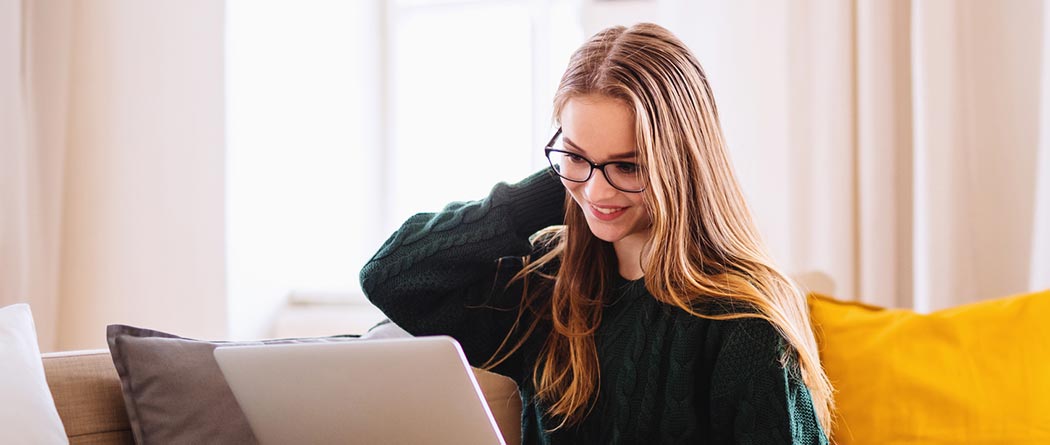 Young woman using laptop on couch at home.