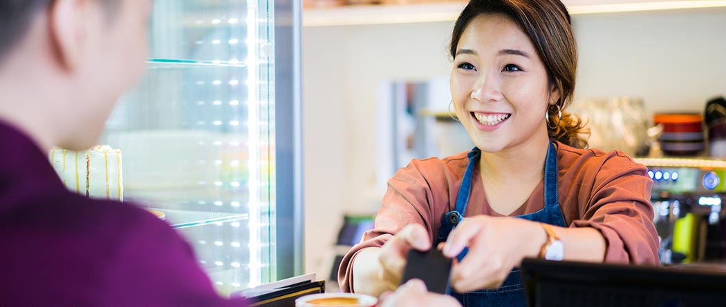 Man handing credit card to woman at cafe.