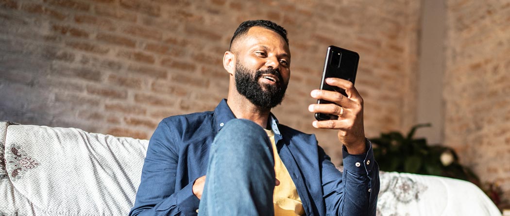 Man looking at phone sitting on floor at home.