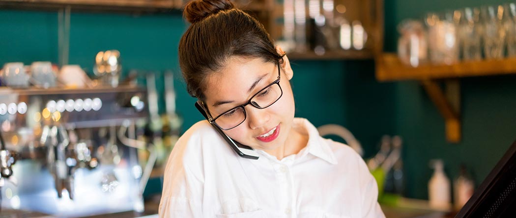 Woman talking on the phone while working at a cafe.