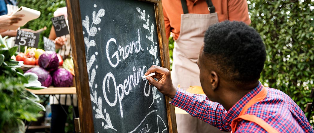 Man writing Grand Opening on chalkboard.