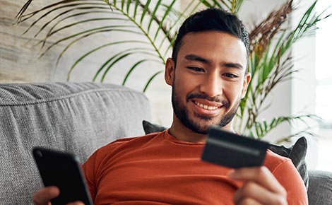 Man holding phone and looking at credit card.